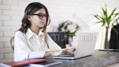 年轻女子在电脑上打字，喝咖啡